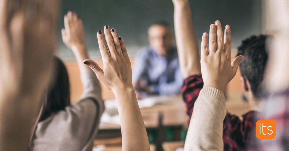 Schüler im Klassenzimmer mit erhobenen Händen